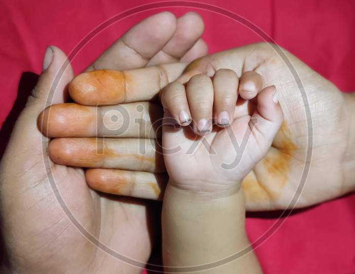 Parents Holding The Kid Palm In Hand Showing The Love