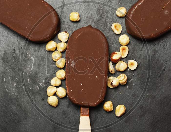 Top View Of Chocolate Ice Cream On Slate Plate With Hazelnuts. Flat Lay