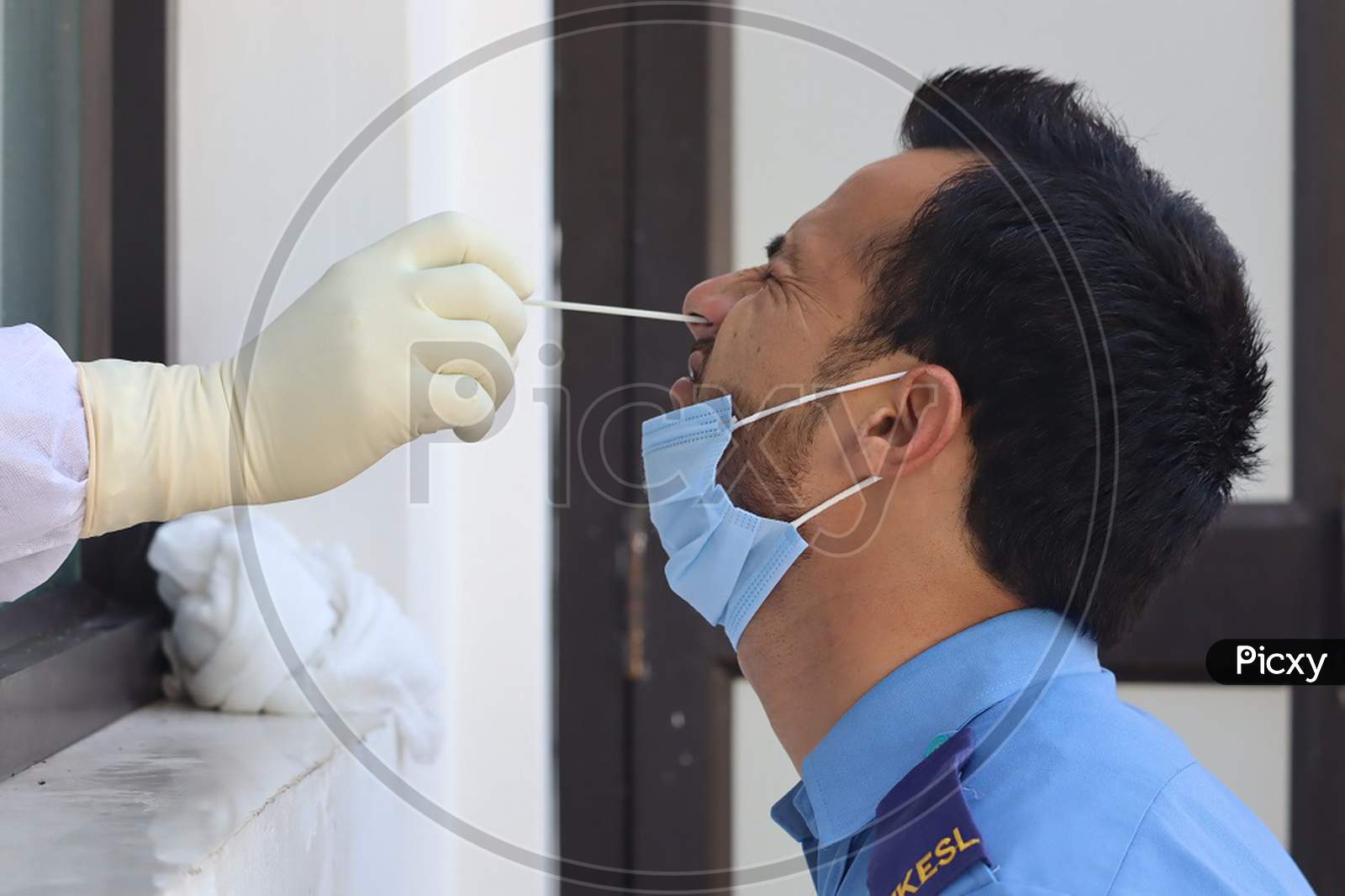 Healthcare workers wearing a Personal Protective Equipment(PPE) kit take nasal swab samples from person during corona virus antigen testing at Poonch
