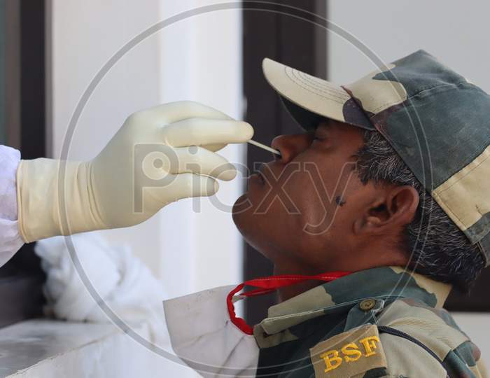 A health worker wearing PPE kit collects samples of a security person for COVID-19 rapid antigen test at Poonch