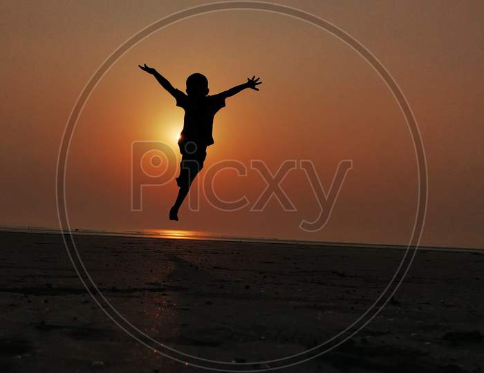 boy jumping in beach with beautiful evening