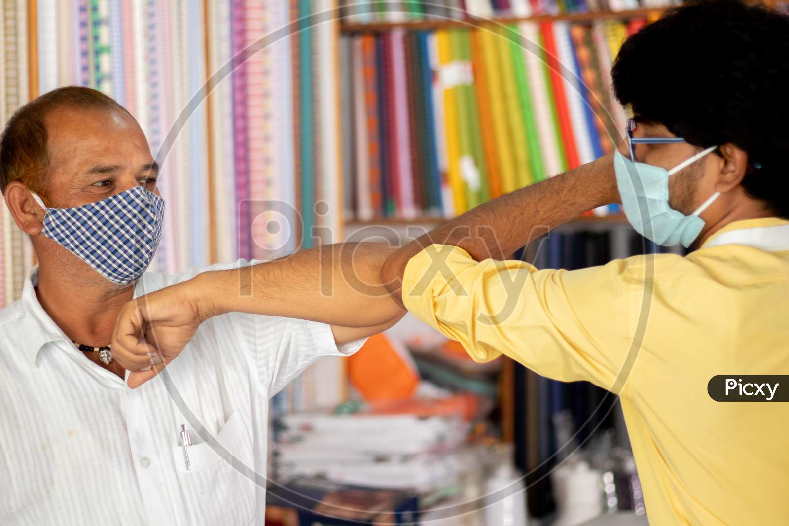 Shopkeeper Greeting Customer With Elbow Bump At Cloth Store - Concept Of People Avoiding Hand Shakes At Business Places To Stop Spreading Coronavirus Or Covid-19.