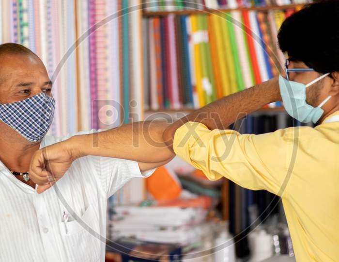 Shopkeeper Greeting Customer With Elbow Bump At Cloth Store - Concept Of People Avoiding Hand Shakes At Business Places To Stop Spreading Coronavirus Or Covid-19.