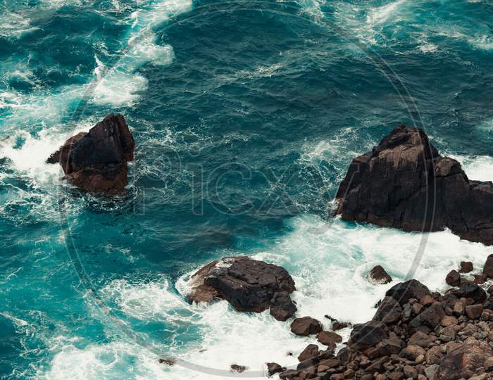 Relaxing Aerial View Of The Ocean Crashing Against The Rocks And The Stones On The Coastline