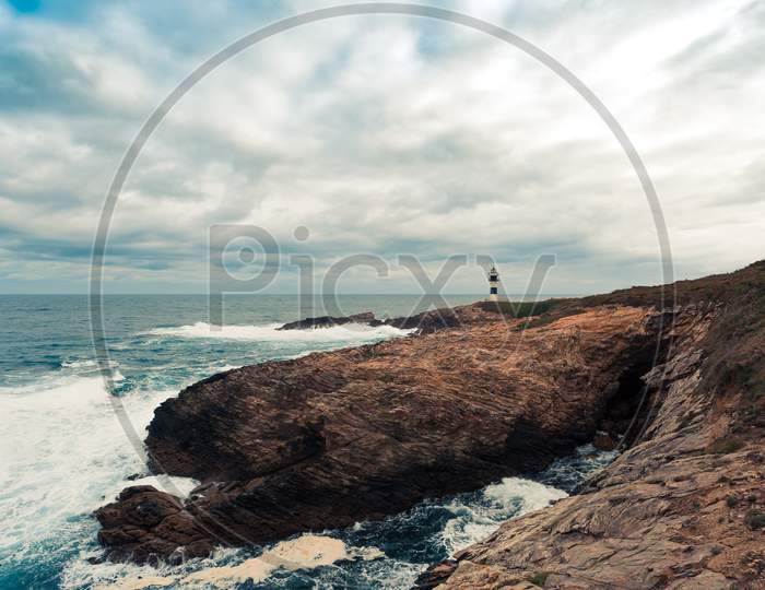 A Wild Lighthouse In The Coast Of The North Of Spains With Giant Rocks An Wild Waves Crashing With Copy Space