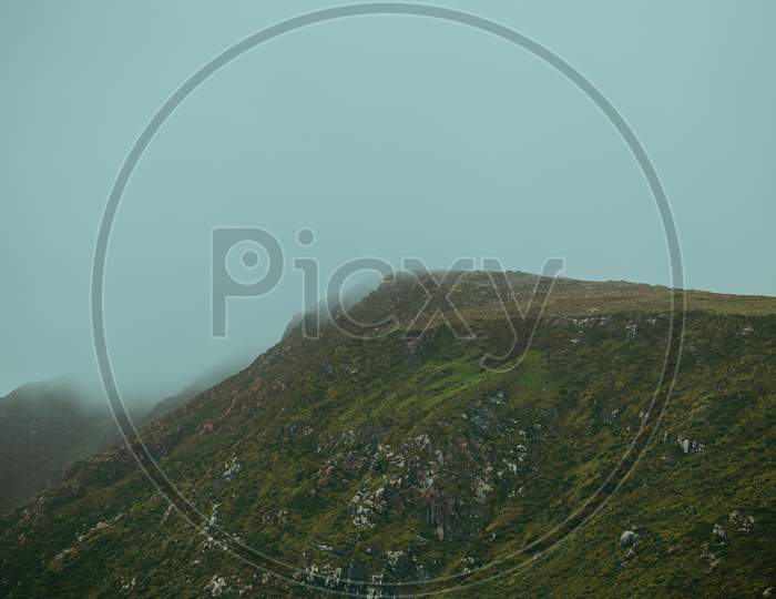 Close Up Of A Mountain With Green Grass All Over It During A Foggy Day With Mist All Over It With Copy Space