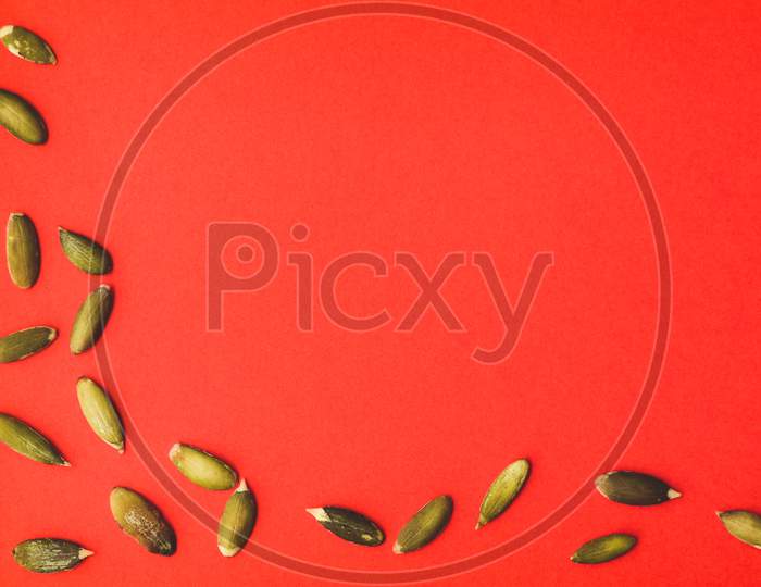 Pumpkin Seeds On Bright Red Background, Empty Space