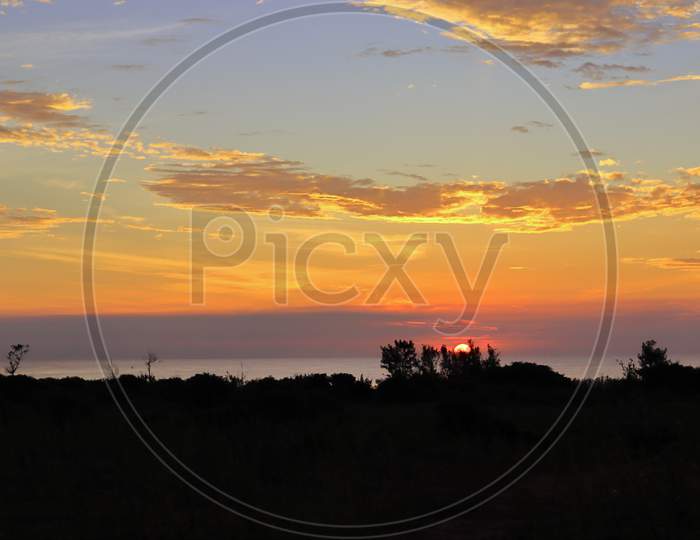 Photograph Of A Landscape With A View Of The Sun Rising From The Sea And Clouds