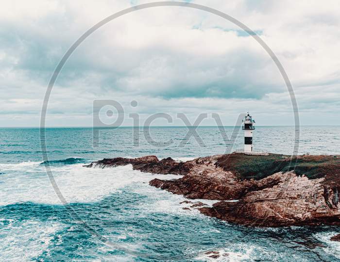 Wild Lighthouse In The Middle Of The Ocean During A Cloudy Day In Coruña Spain With Copy Space
