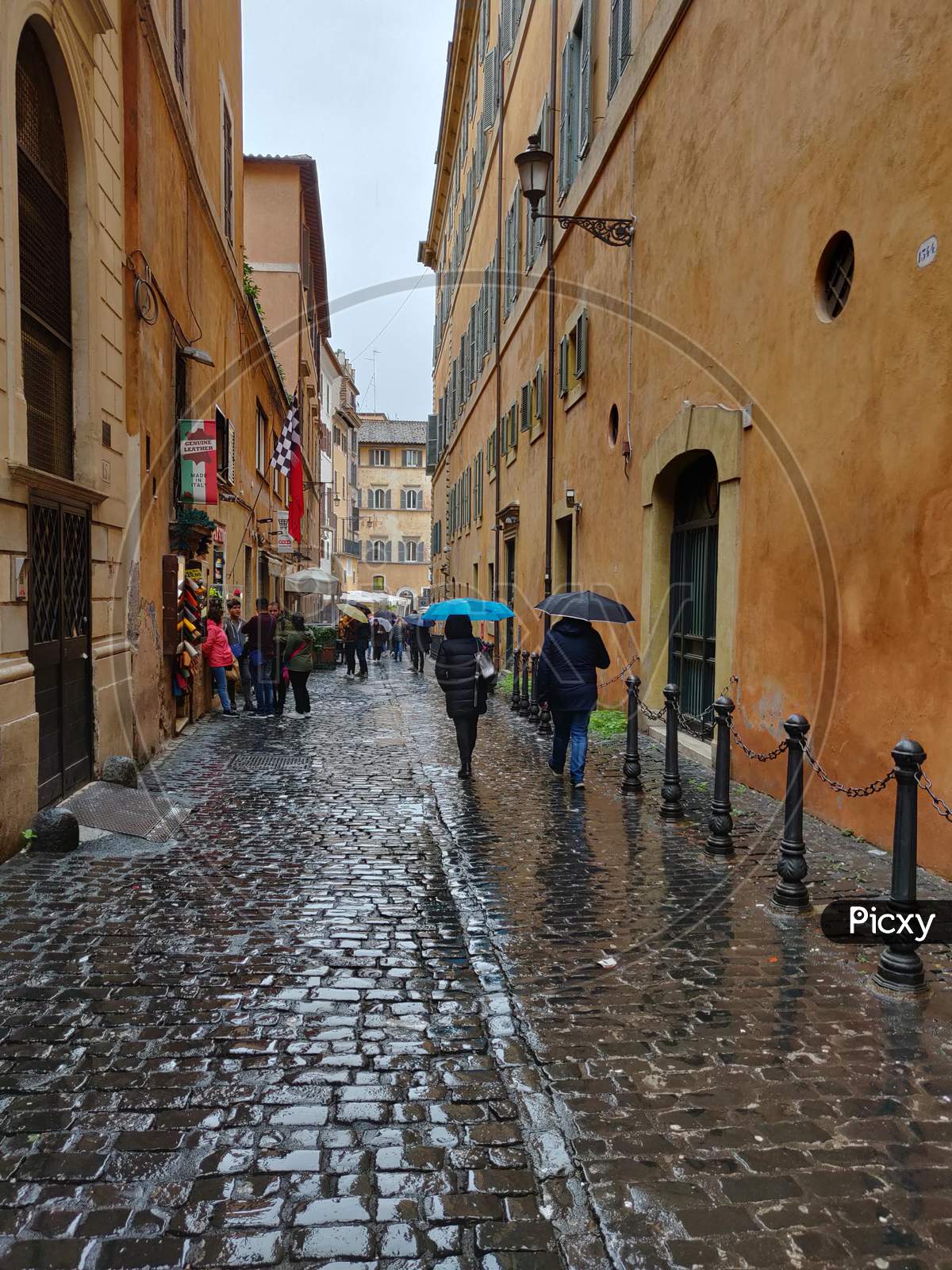 People walking in the rain with umbrella in Via dei Giustiniani