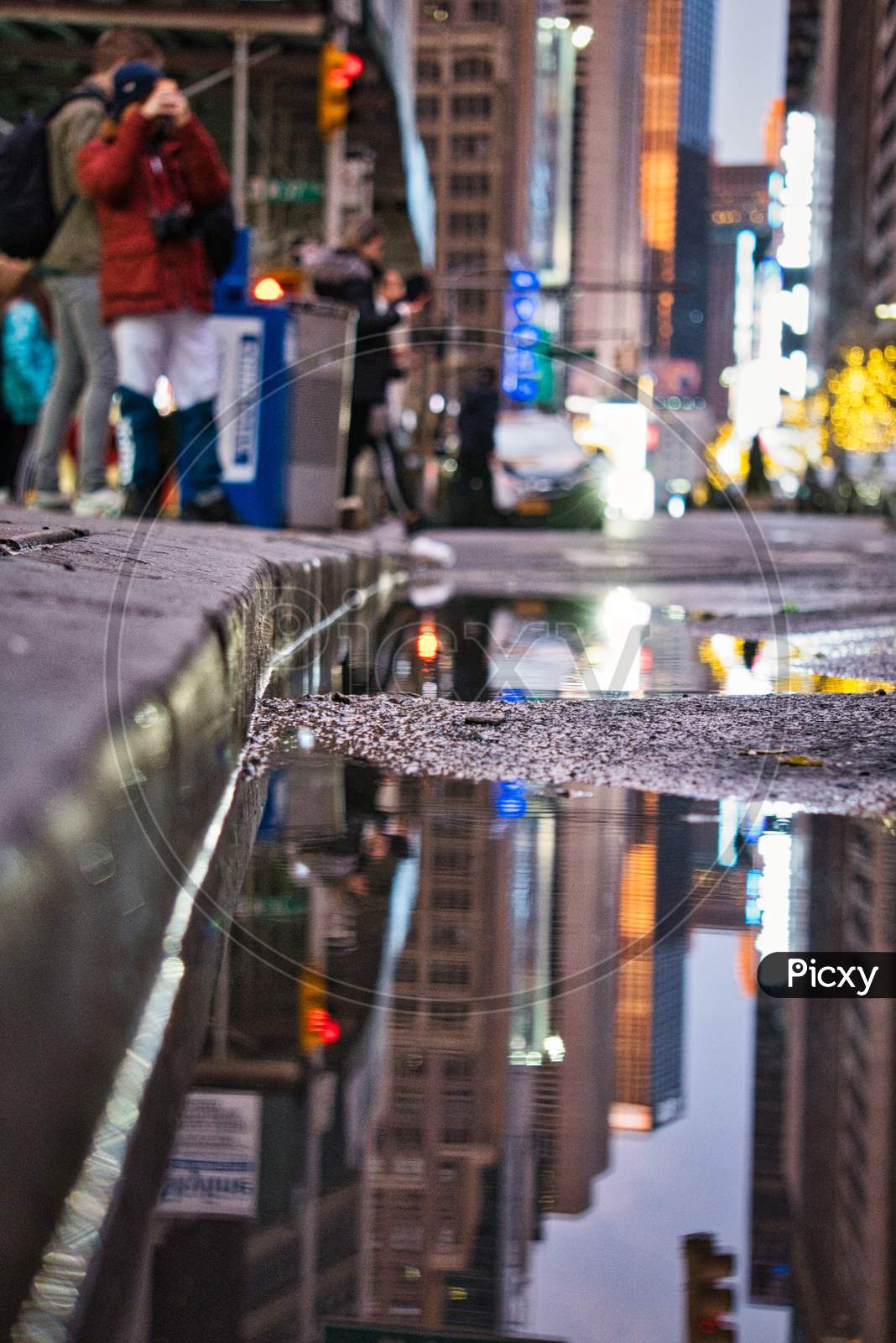 City lights reflecting in the water puddle by the side of the road