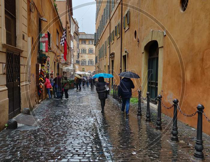 People walking in the rain with umbrella in Via dei Giustiniani