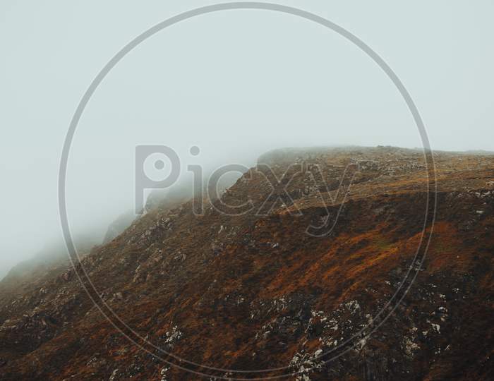 Close Up Of A Massive Red Mountain In The North Of Europe During A Foggy Day With Mist All Over It With Copy Space