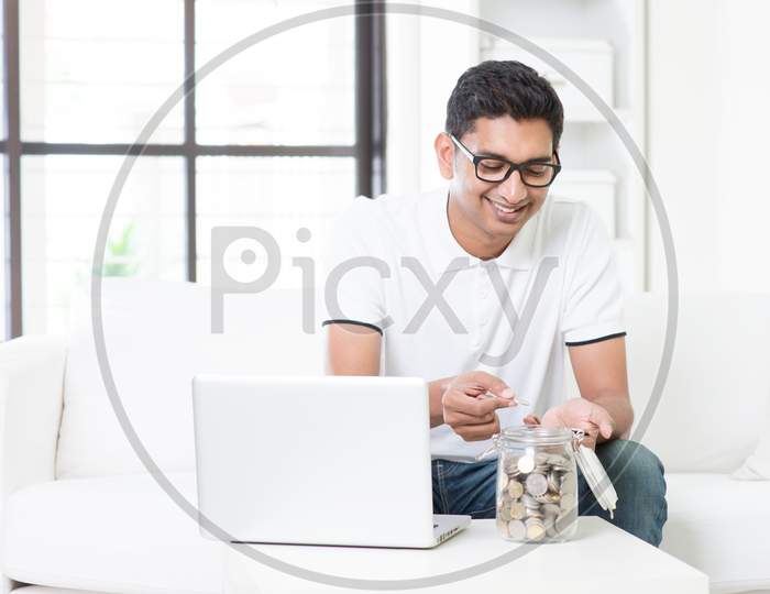 Indian Guy Using Computer And Counting Money At Home