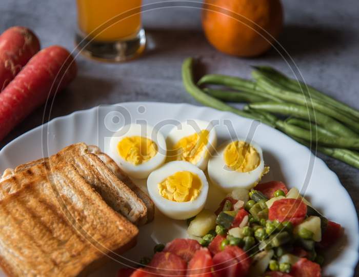 Close up of healthy food items bread slices, boiled vegetables and eggs in a plate