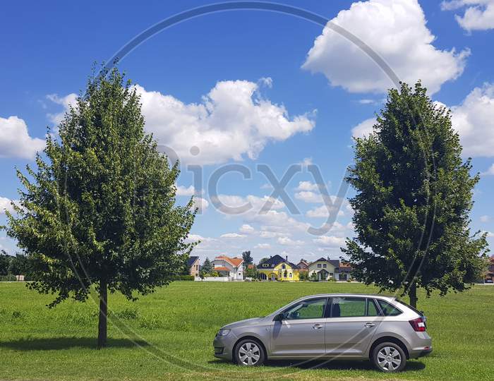 Car In Front Of Two Green Canopies, Symmetrical, In The Park. Sunny Day With Clouds