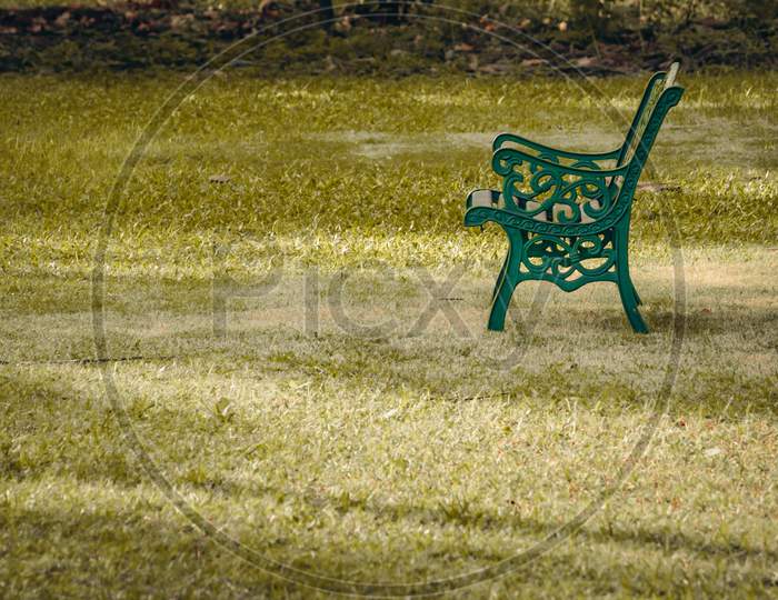 A Steel Bench In A Green Grass Field. Empty Chair In A Park.