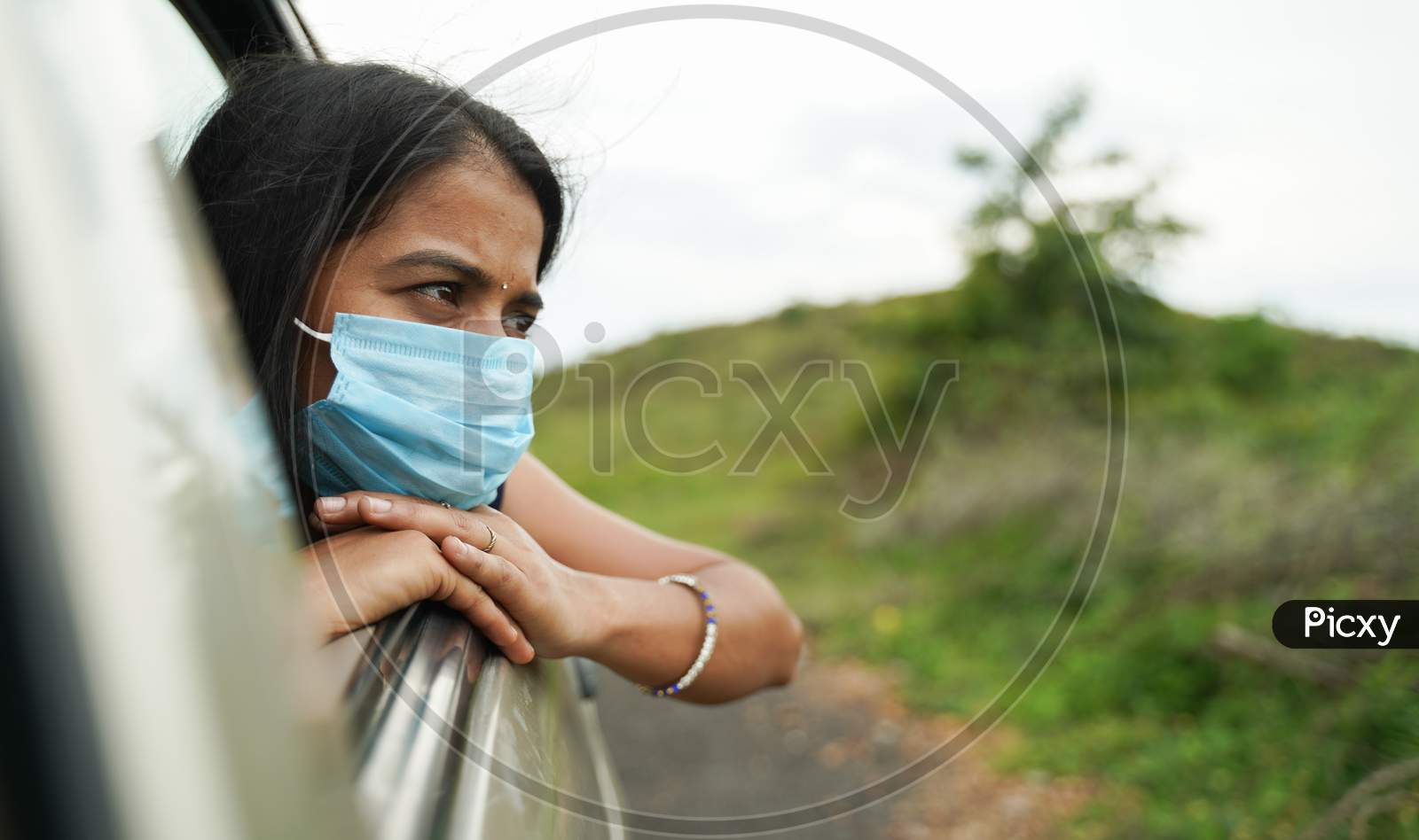 Sad Young Girl In Medical Mask Watching Out From Car Window - Concept Of Travel, Vacation And Road Trip After Covid-19 Or Coronavirus Pandemic