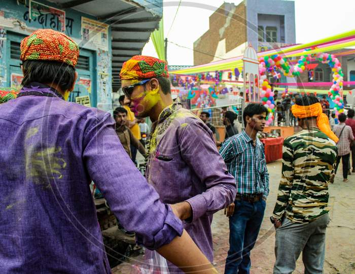Mathura, Uttar Pradesh/ India- January 6 2020: Group Of Friends Standing On A Decorated Place And Faces Smeared With Colors , Wearing Traditional Cap, Conversation To Each Other While Celebrating Holi Festival.