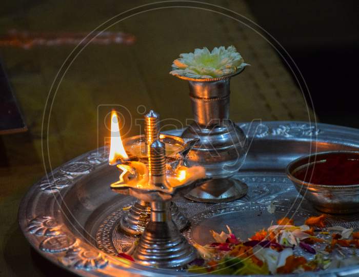 Side View Of Beautiful Silver Oil Lamp And Pooja Thali Decorated For Worshiping God.
