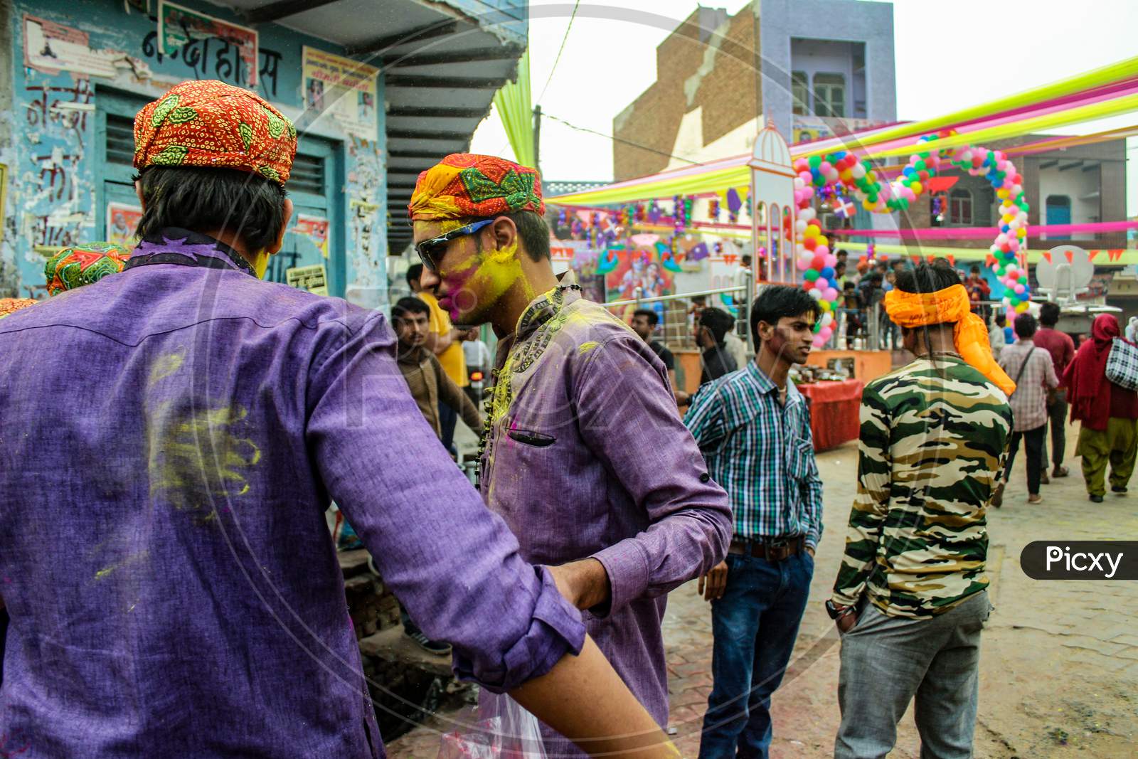 Mathura, Uttar Pradesh/ India- January 6 2020: Group Of Friends Standing On A Decorated Place And Faces Smeared With Colors , Wearing Traditional Cap, Conversation To Each Other While Celebrating Holi Festival.