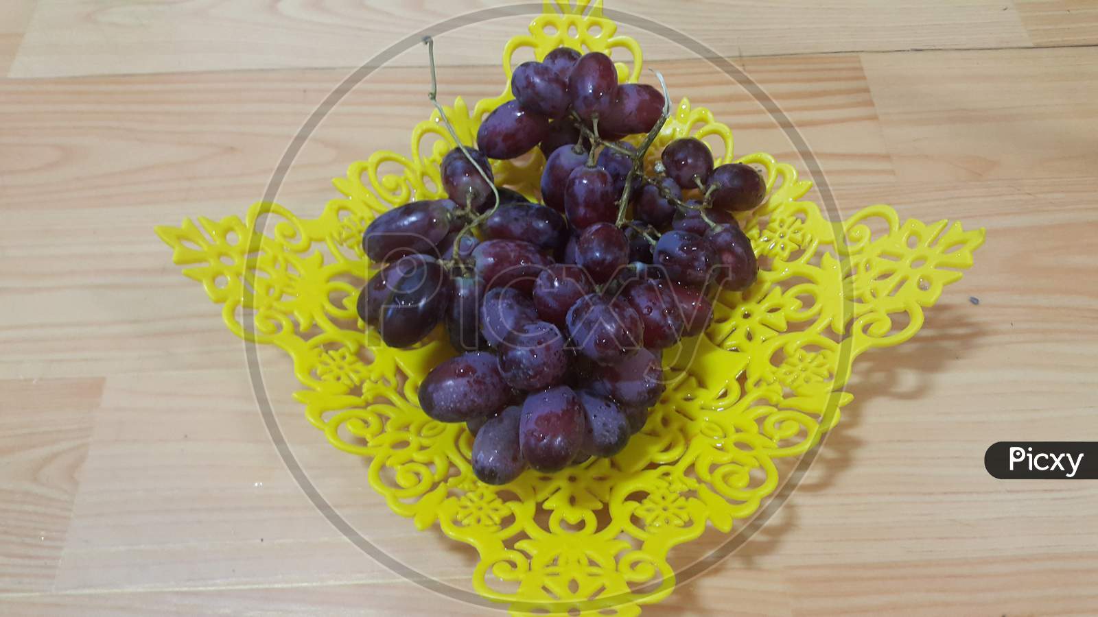 Close Up View Of Bunches Of Brown Grapes Served In Yellow Plastic Fruit Tray