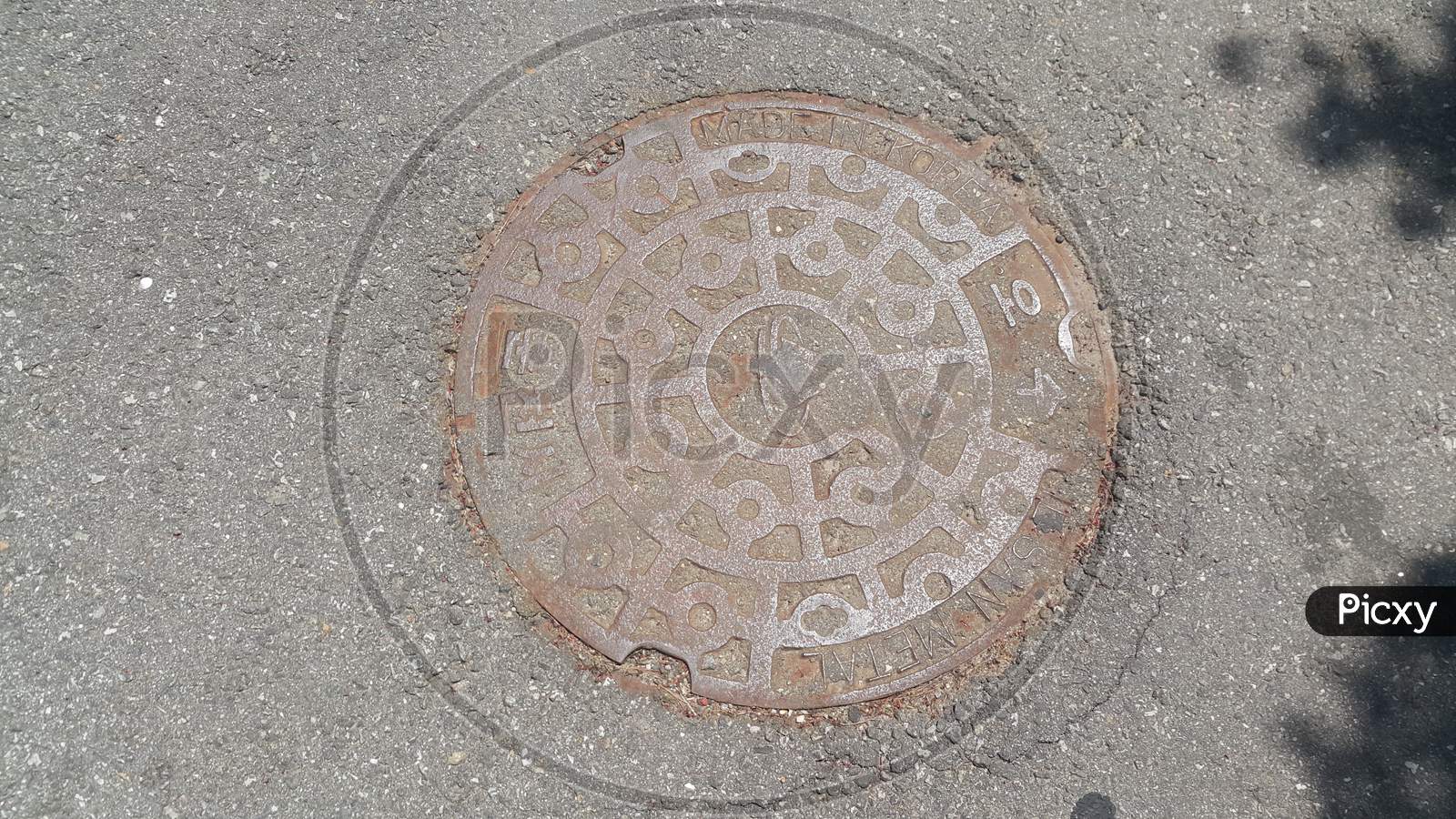 Top View Of A Manhole Cover On Drainage Or Sewerage Under Paved Road.