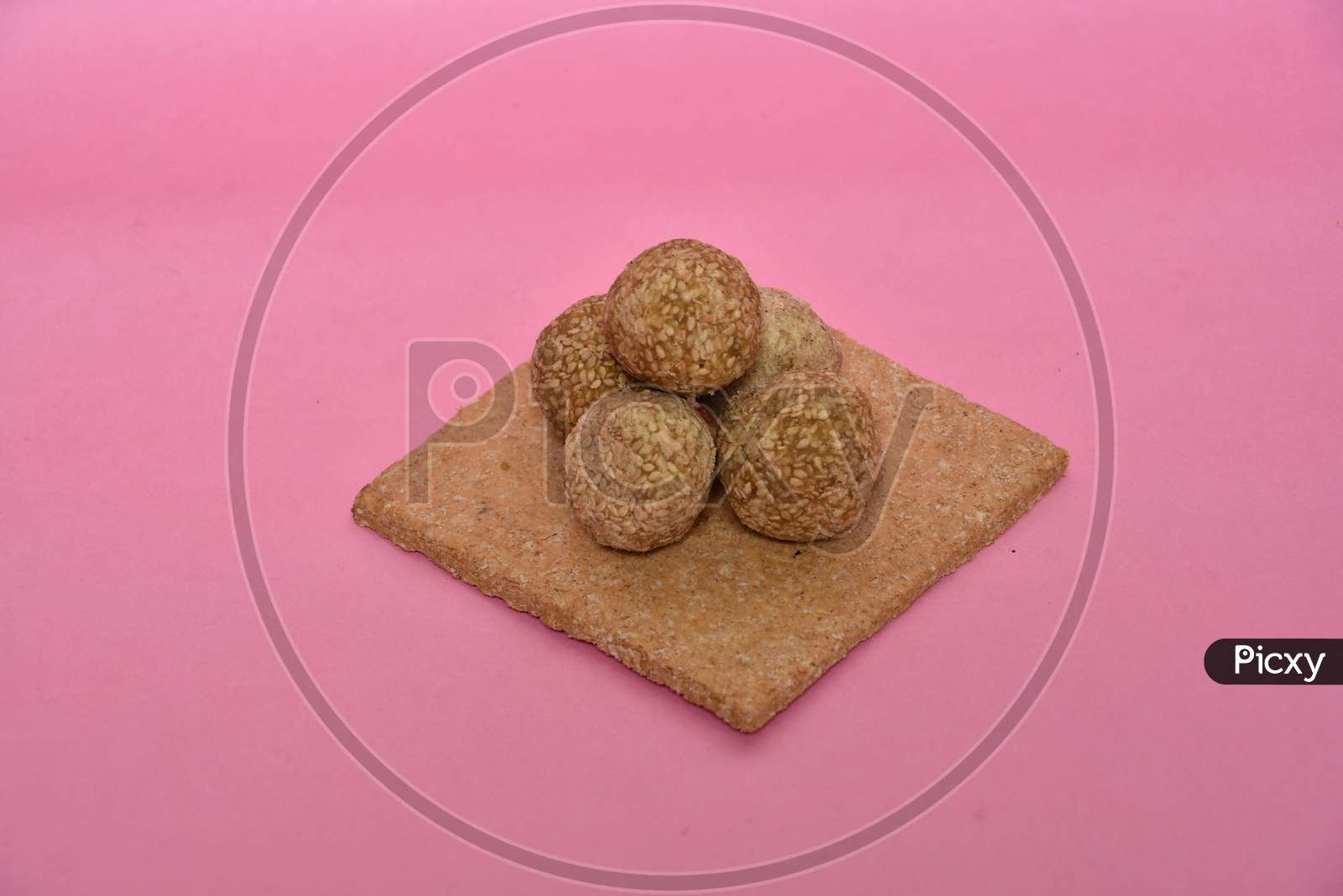 Indian sweet dish,Sesame seeds ball or called in hindi, til ke laddu on pink background