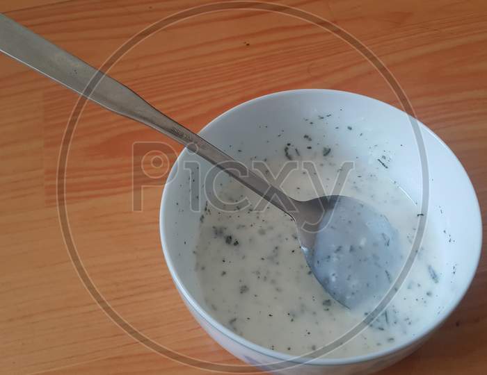 Close Up Of Plain Curd Or Yogurt Or Dahi In White Ceramic Bowl With Silver Spoon