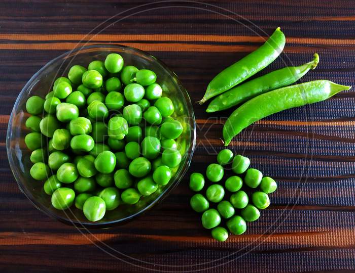 Fresh Green Peas with Pea Pods on an Isolated Brown background