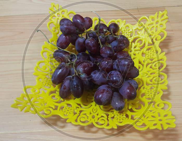 Close Up View Of Bunches Of Brown Grapes Served In Yellow Plastic Fruit Tray