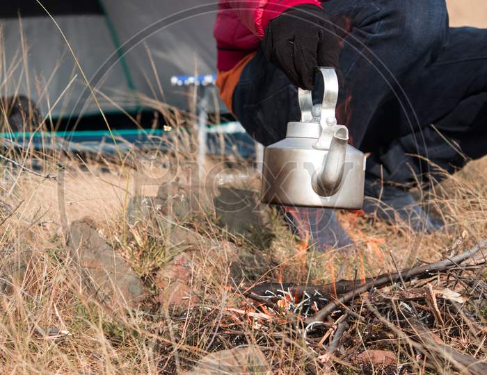 Close Up Shot Of Hiker Heating Up Teapot Or Coffee Using Campfire During Camping.