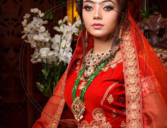 Image of Magnificent Young Indian Bride In Luxurious Bridal Costume With  Makeup And Heavy Jewellery Is Sitting In A Chair In With Classic Vintage  Interior In Studio Lighting. Wedding Fashion.-GC704229-Picxy