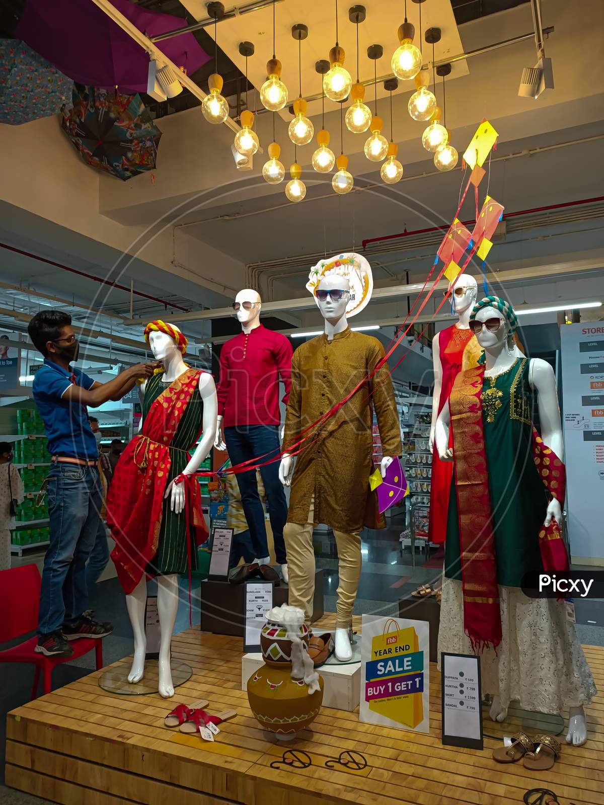 A Beautiful evening scene at a Shopping Bazaar where a Staff is seen dressing up a Mannequin with a  traditional Indian Ladies Kurtis dress at Mysuru,India.
