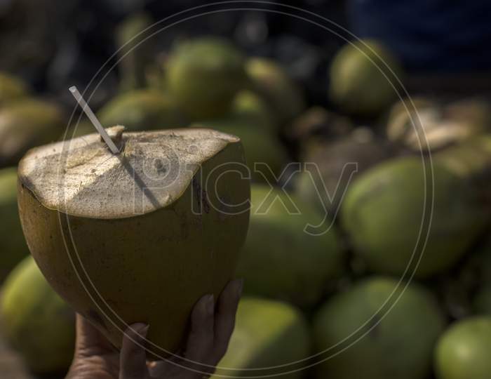 Close Up Shot Of A Green Coconut Fruit Juice With Straw Holding By A Male Hand.