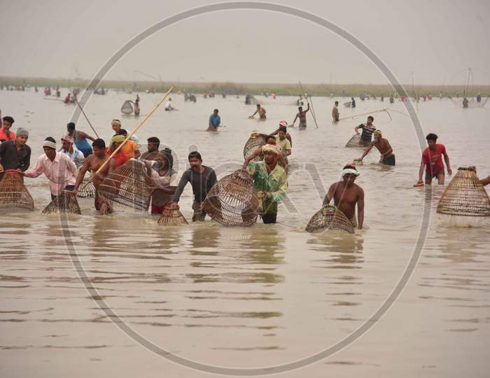 villagers participating in community fishing as part of Bhogali Bihu celebrations are seen through a traditional fishing tool at Dighali Lake in Nagaon district, in the northeastern state of Assam on Jan 13,2021