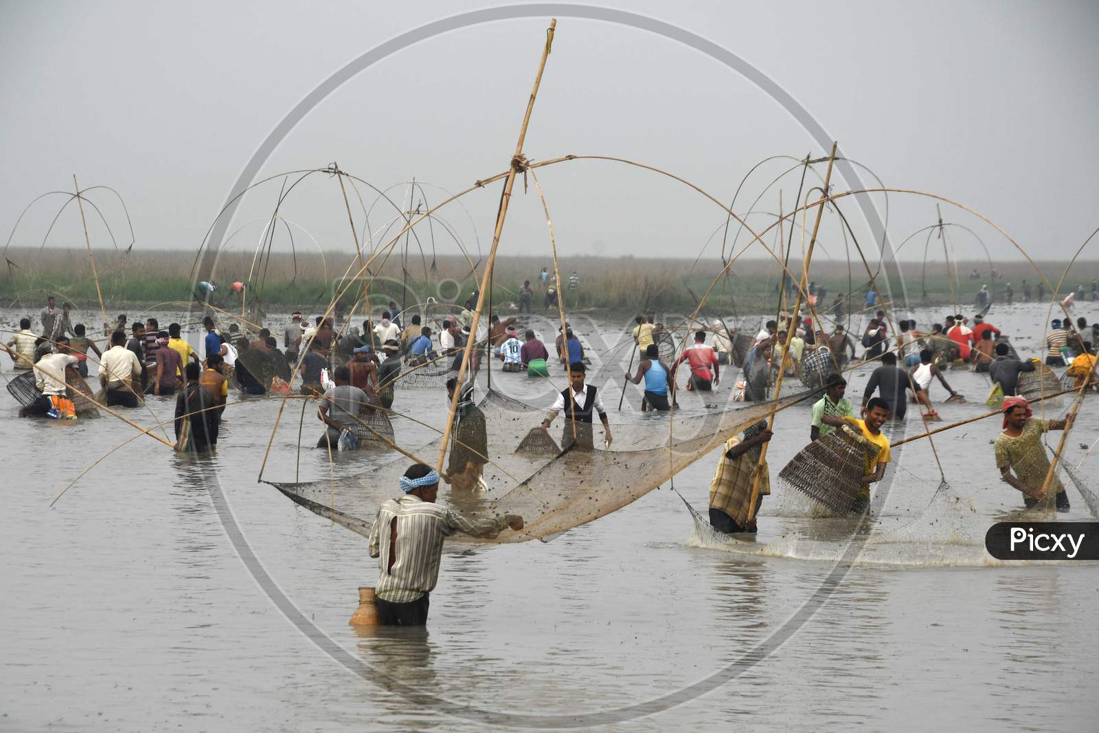villagers participating in community fishing as part of Bhogali Bihu celebrations are seen through a traditional fishing tool at Dighali Lake in Nagaon district, in the northeastern state of Assam on Jan 13,2021