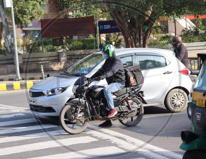 Delhi, India - Jan 2021 , Connaught place market after lockdown. A swiggy food delivery boy with order in traffic
