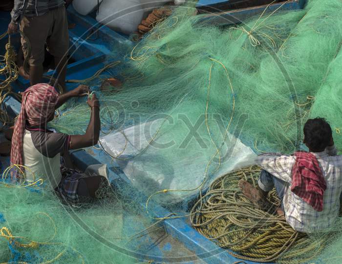Some Fishermen Repairing Their Fishing Net Before Going To Sea For Fishing.