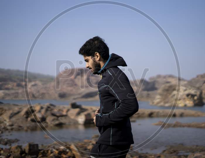 Young Indian Fit Boy Jogging In The Morning Near A Lake Situation In Middle Of A Mountain Area.