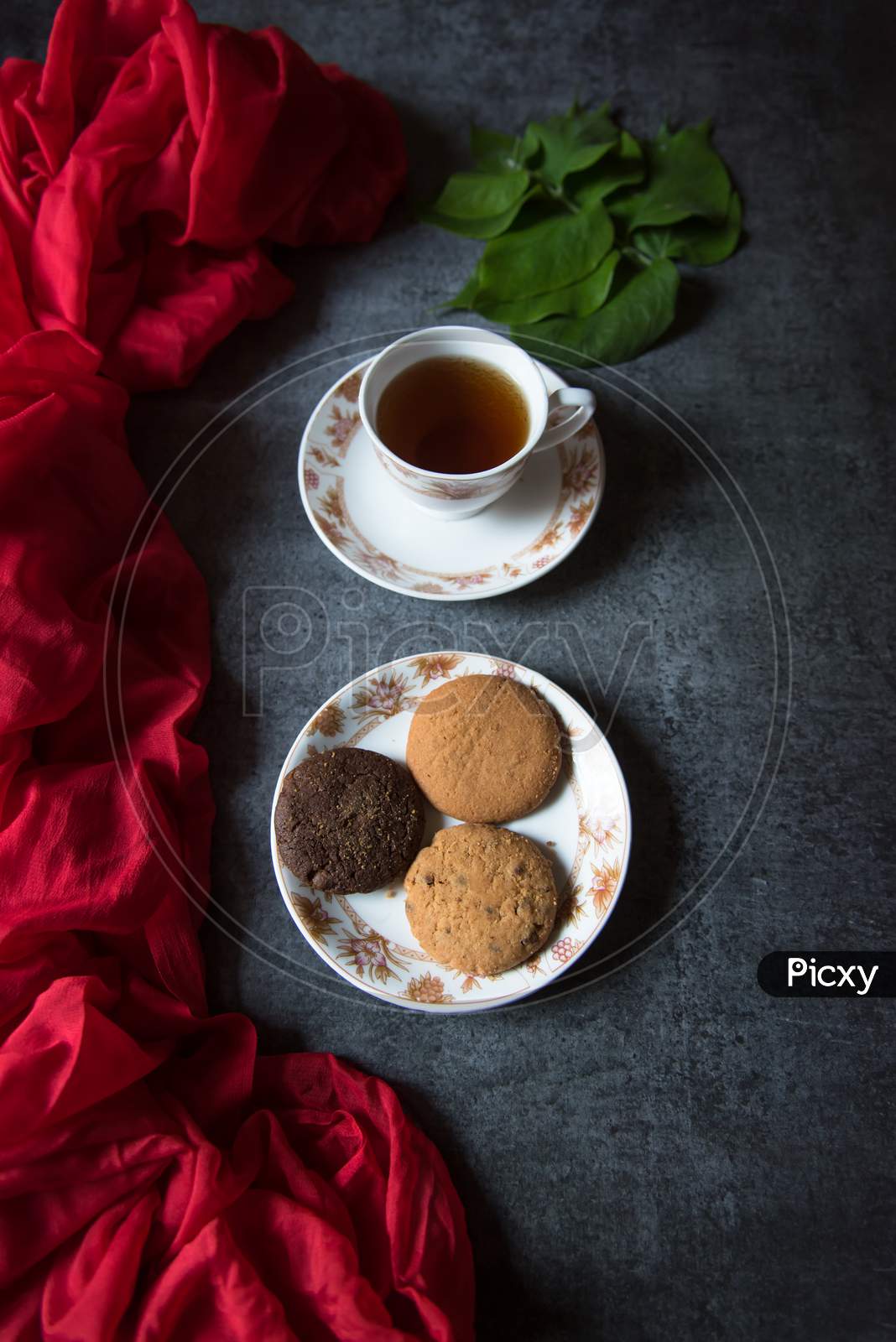 Top view of a cup of tea and a plate of cookies on a background