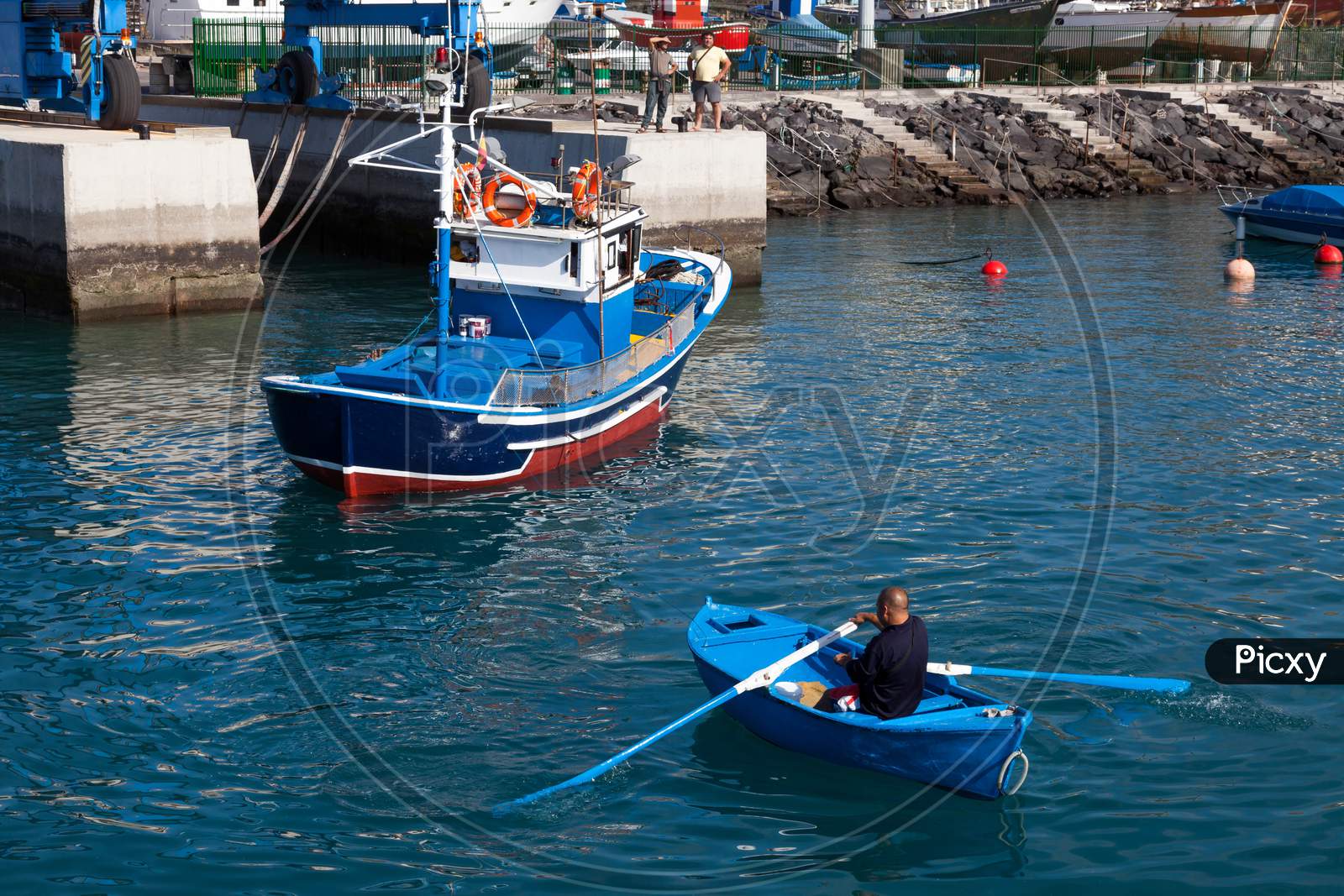 Man Rowing A Fishing Boat To Side Of Harbour In Tenerife