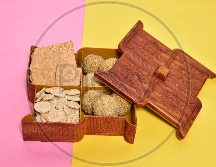 indian festival makar sankranti concept  sesame seed ball or til ke laddo and tilgul in box and colorful paper background