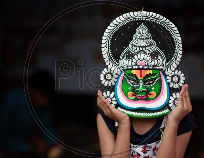 kid girl holding an asian mask and posing