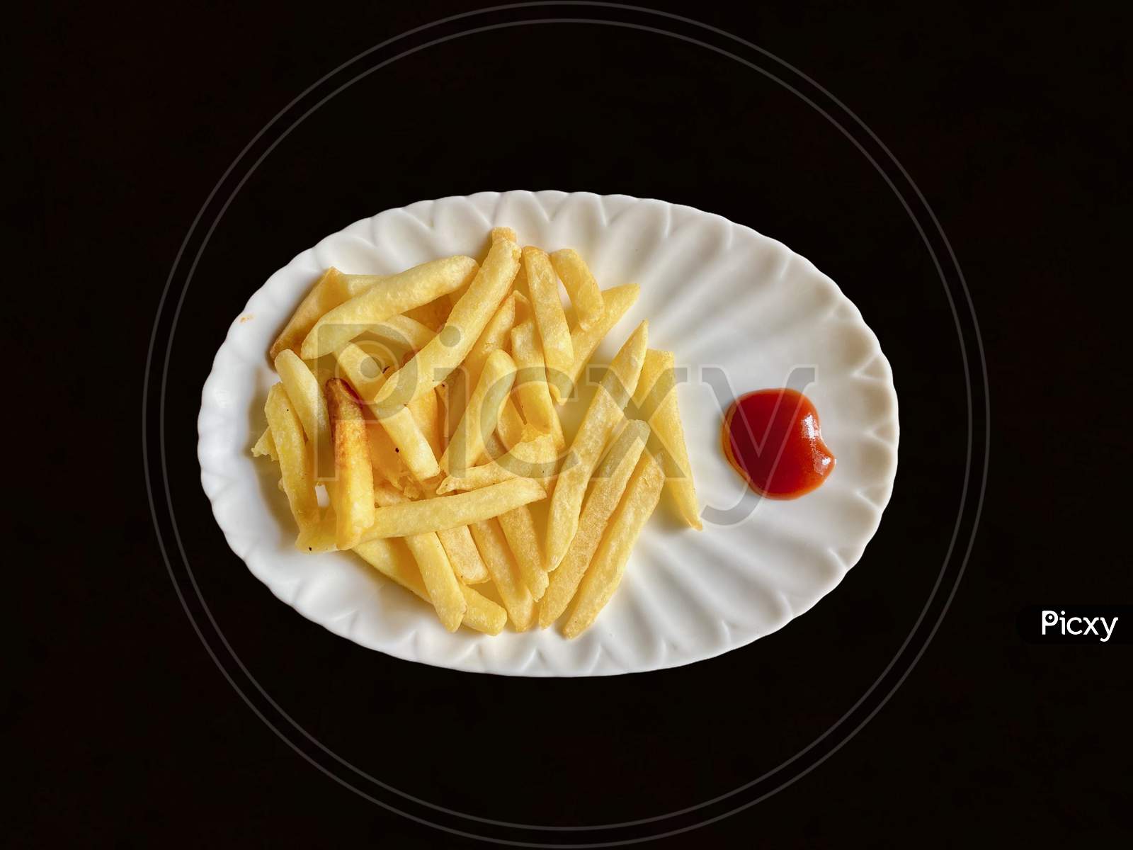 French Fries With Tomato Sauce Being Served In A Plate