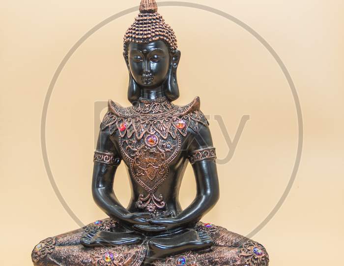 A Small Image Of Buddha In Lotus Position Isolated On Light Background