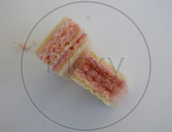 Broken pieces of multiple layered strawberry fruit flavor cream filled wafers isolated on white background
