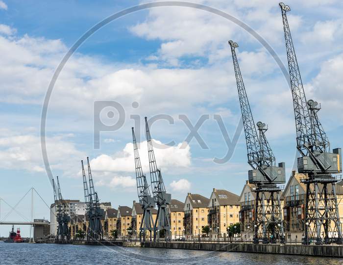 Old Dockside Cranes Alongside A Waterfront Development