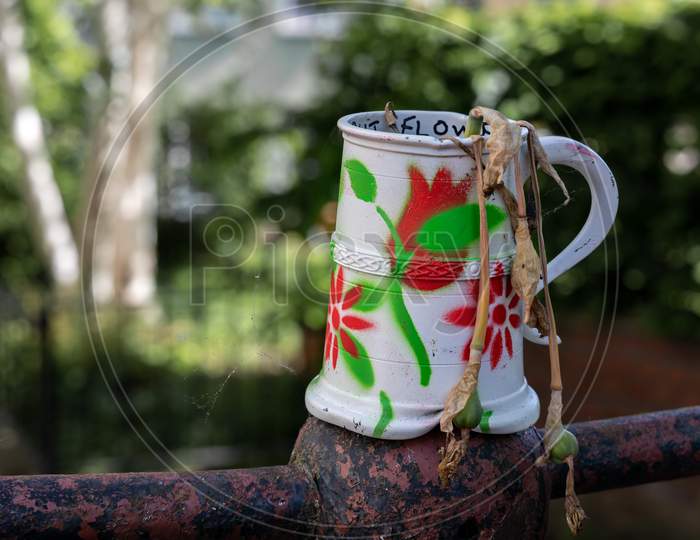 Old Dented And Painted Tankard Containing Dead Daffodils