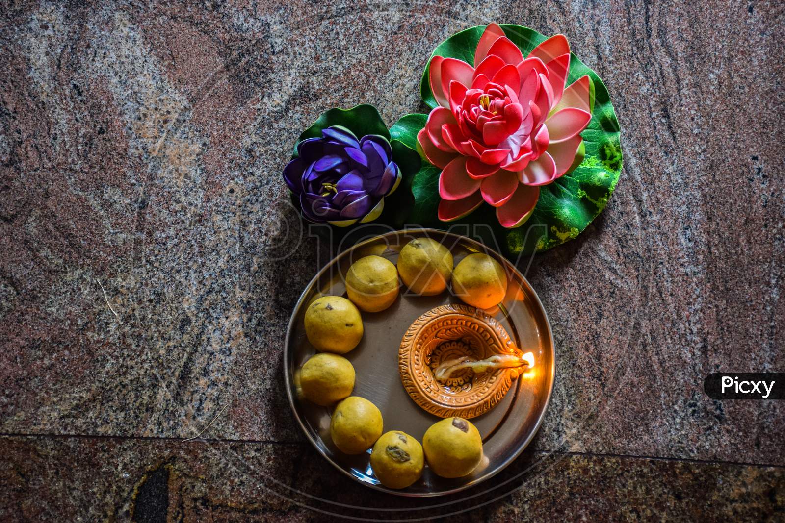 Delicious Gram Flours Sweet Dish ,Made Up During Diwali Festival In India. Decorated With Flowers And Oil Lamp.